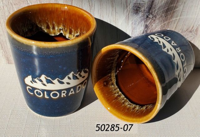50285-07 Colorado souvenir shot, ceramic with a dark blue reactive glaze exterior and brown glaze interior and debossed mountains design