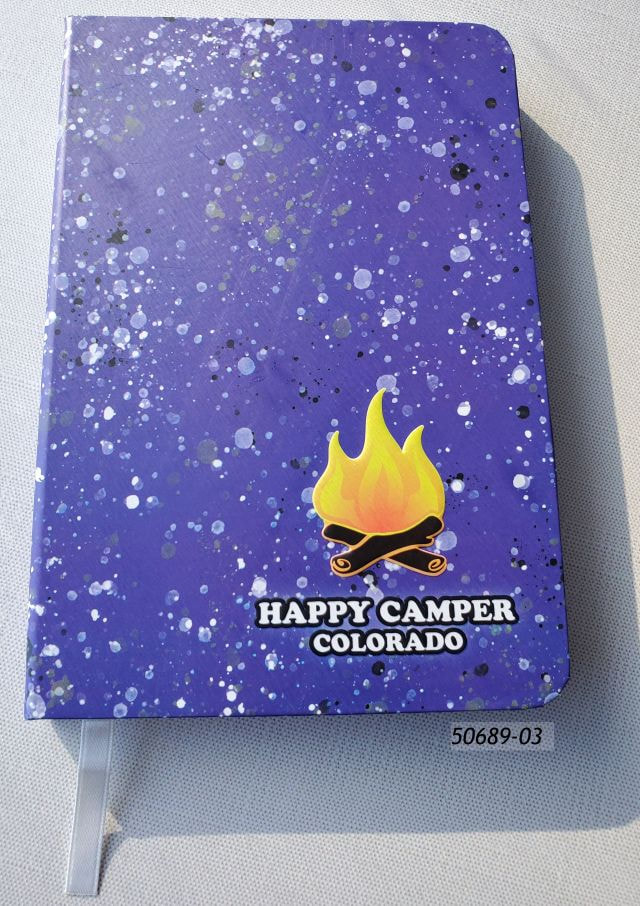 50689-03 Colorado Souvenir Journal Book with lined pages.  Cover design is blue speckle with a campfire that reads Happy Camper Colorado